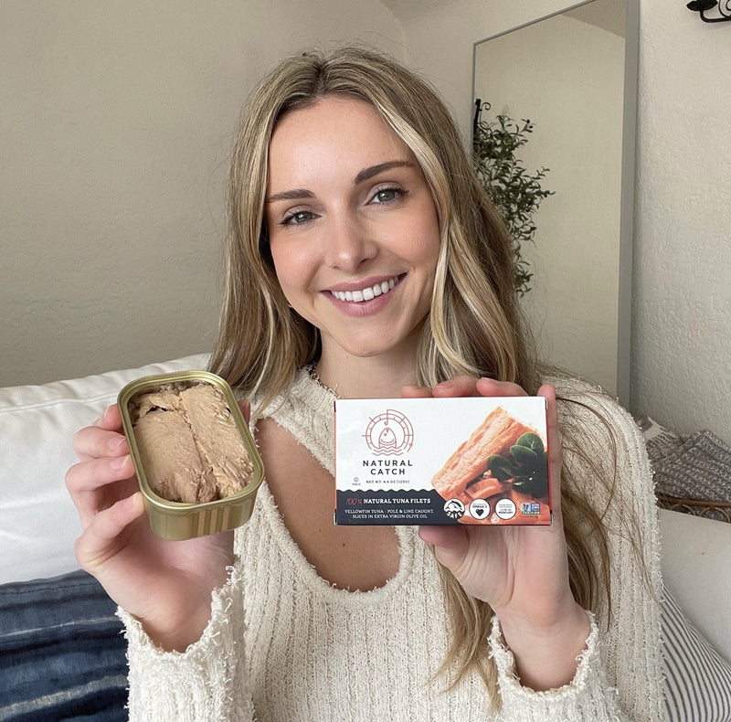 Pearl holding an open can and box of Natural Catch Albacore in EVOO