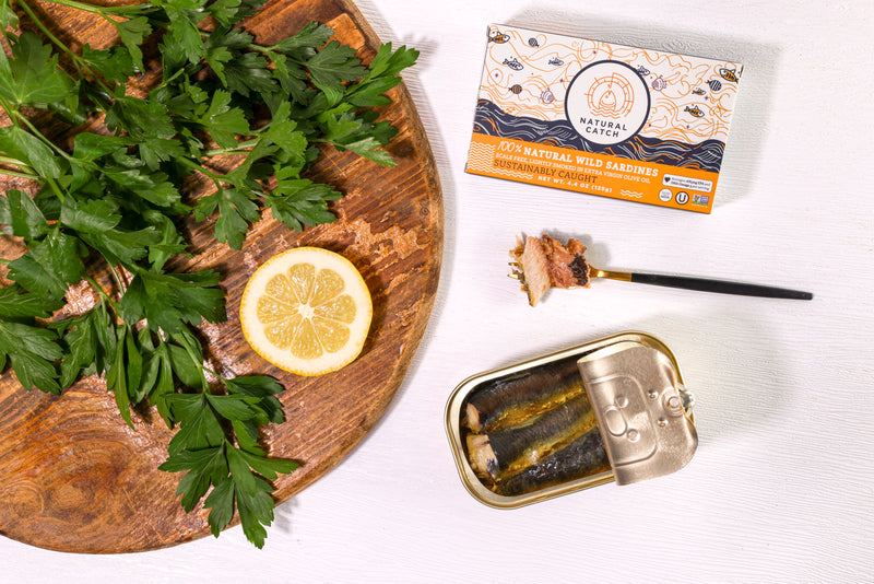 Open can of Natural Catch Sardines with a fork, parsley and lemon
