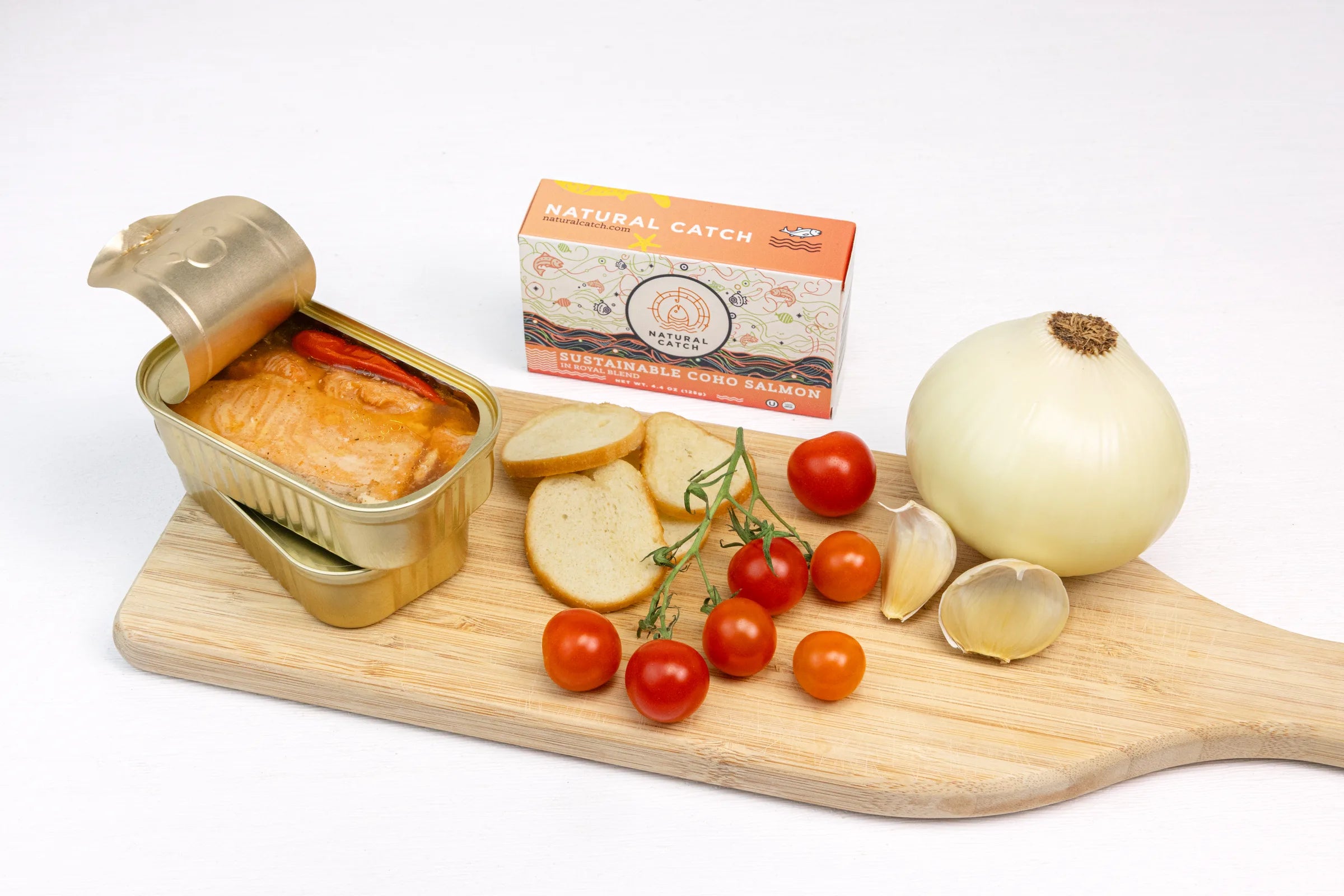 Gold tin of Coho salmon on board with tomatoes, garlic, and herbs
