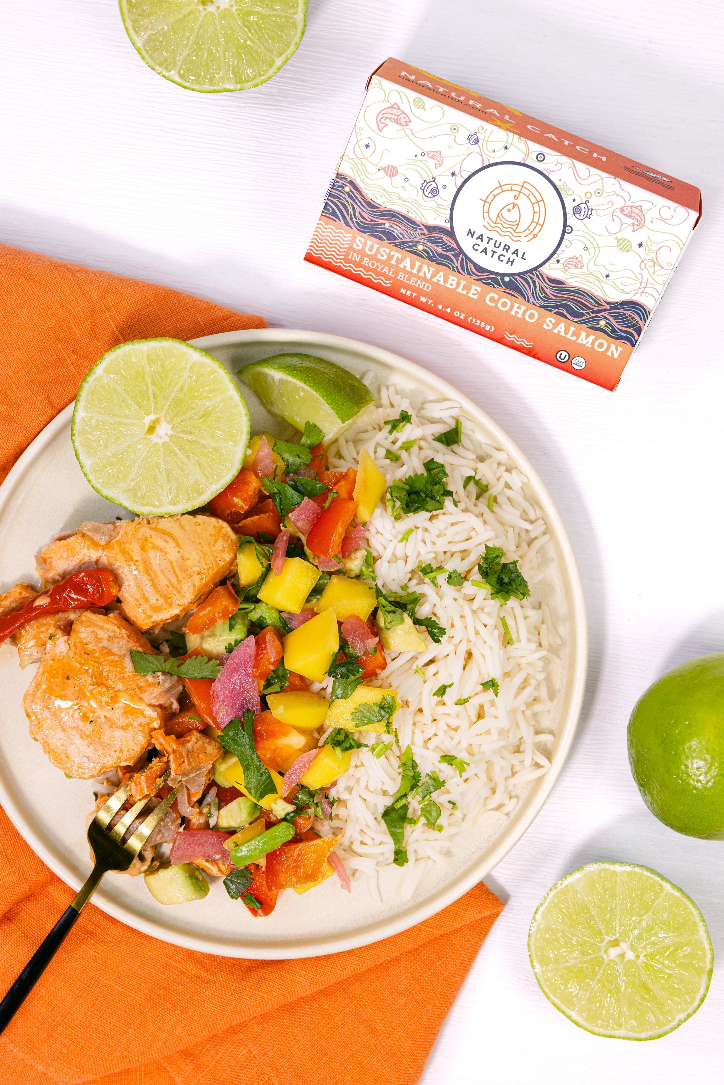 Plated Coho salmon with vegetable medley, white rice, and lime wedges