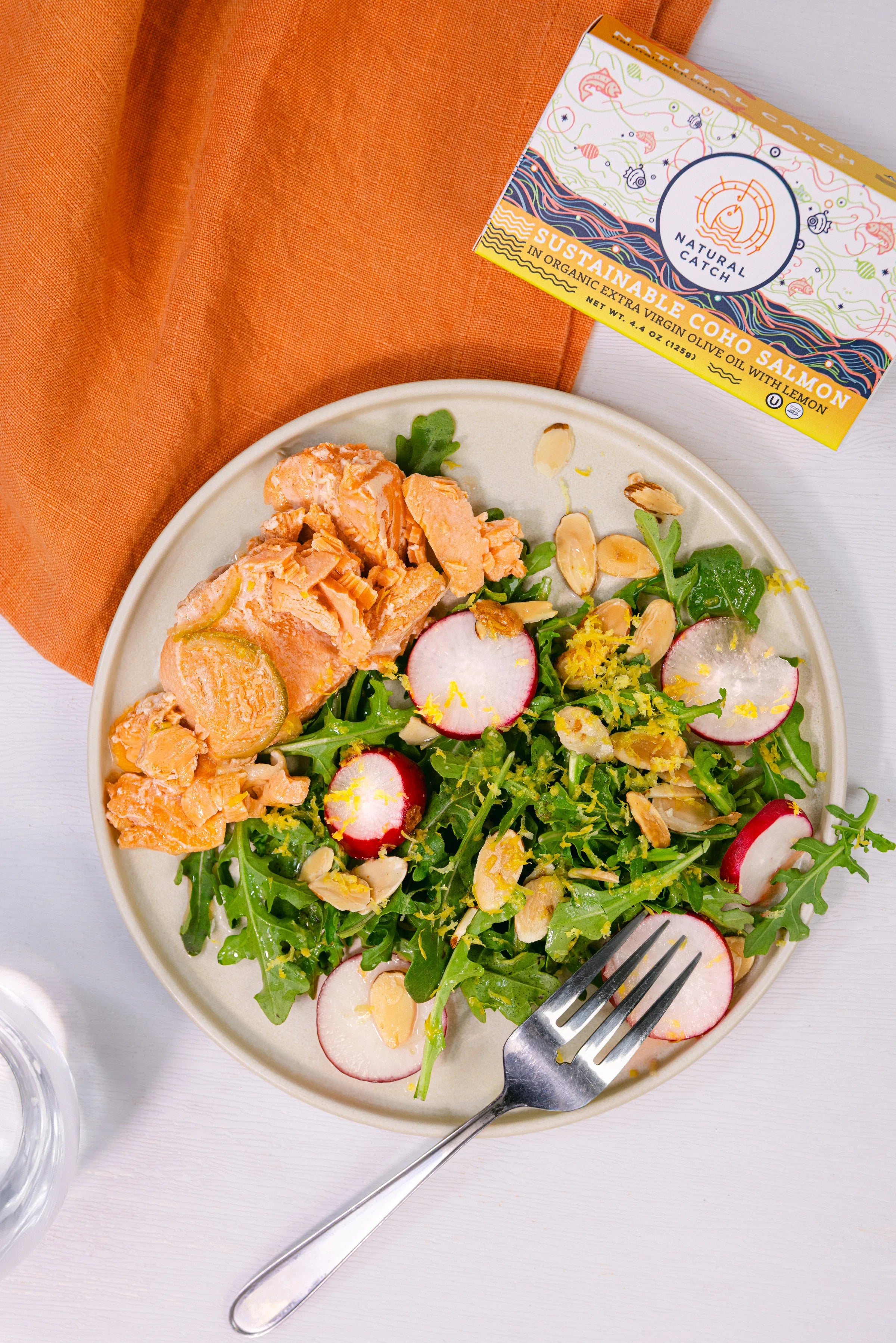 Plated Coho salmon salad with fresh greens, sliced radishes, and toasted almonds